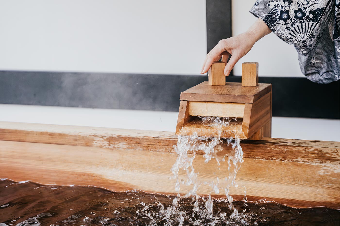 Hot water flowing from a wooden spout into the hinoki bath