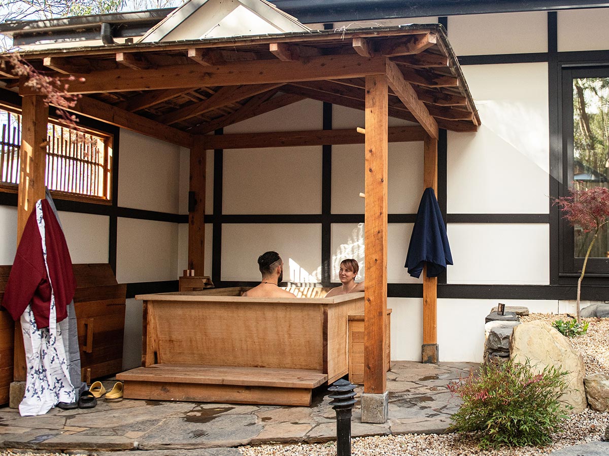 The private courtyard bathhouse, steam rising from the hinoki tub