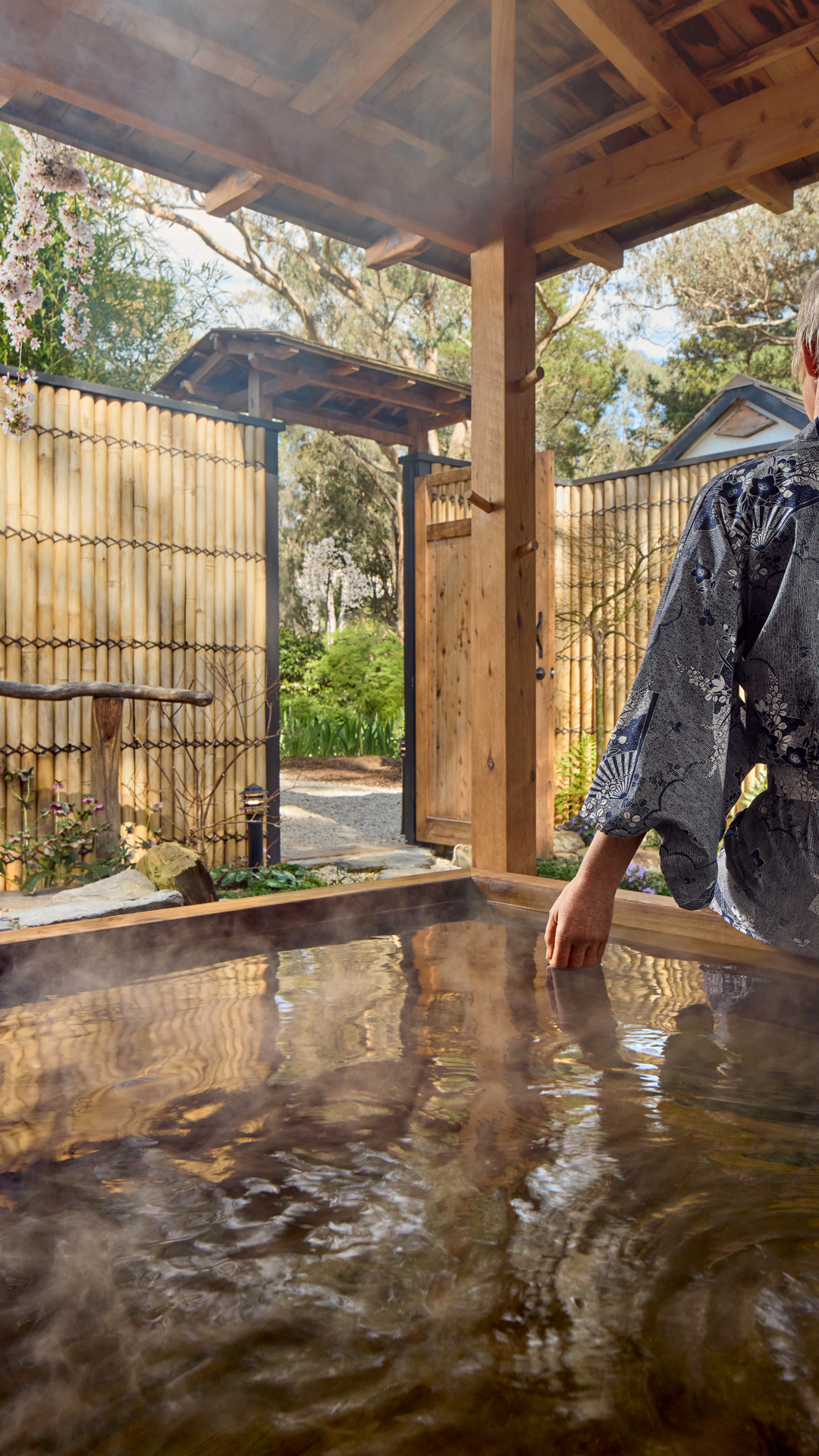 A guest in yukata at the outdoor hinoki bath at Shizuka Ryokan