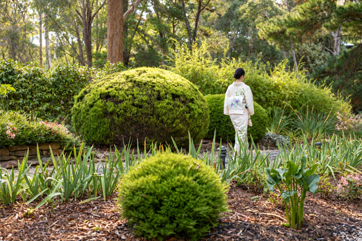 A guest walking slowly through the woodland garden at Shizuka Ryokan