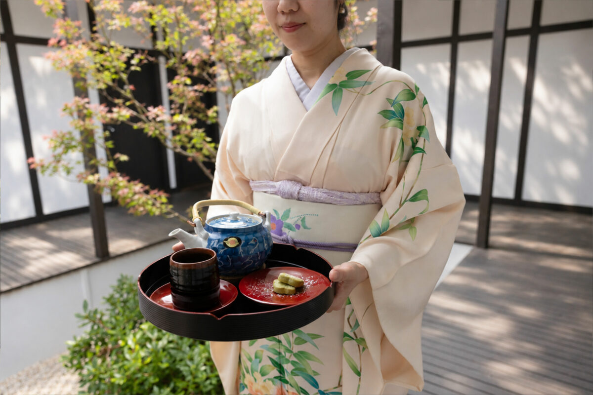 A member of the Shizuka team in kimono carrying a tea tray
